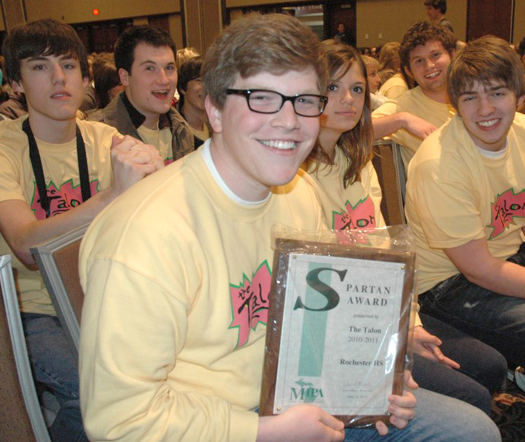 A student holds a Spartan Award plaque