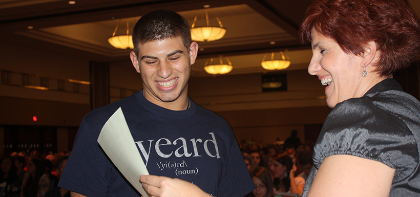 A yearbook student wearing a yeard shirt receives an award