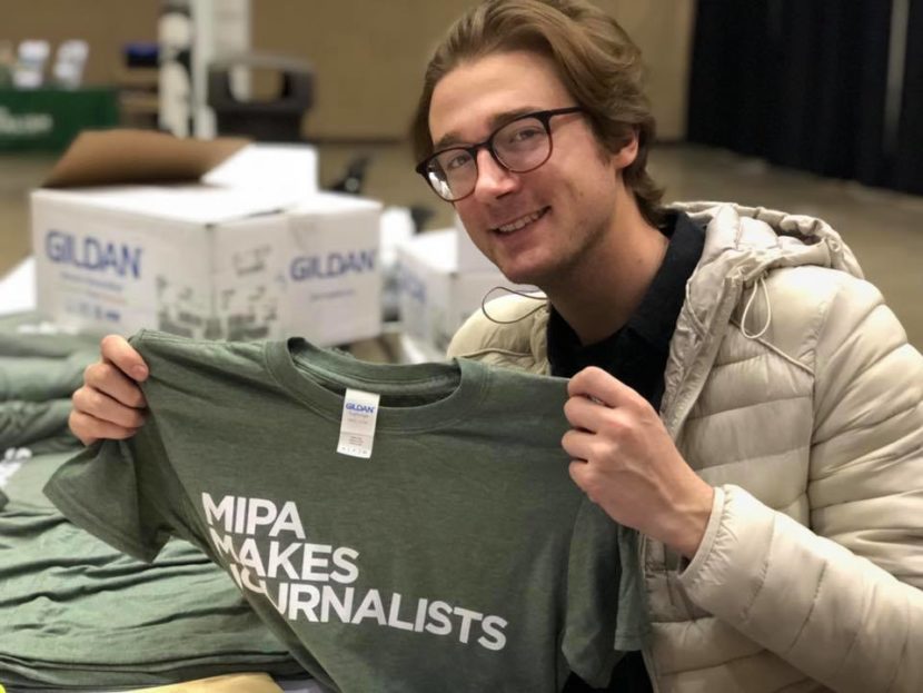 MIPA office staff member holding a MIPA Makes Journalists T-shirt