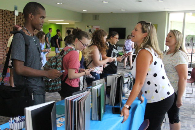Participants talk with representatives of a yearbook publishing company.