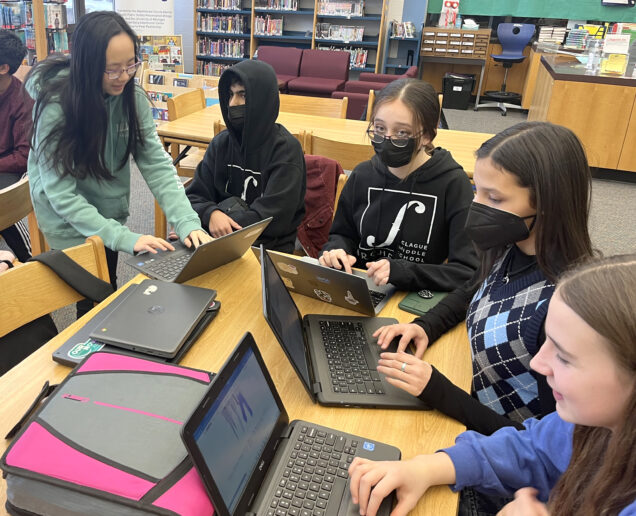 The Cougar Star Editor-in-Chief Mia Lin (left) works with members of the newspaper club at Clague Middle School in Ann Arbor.