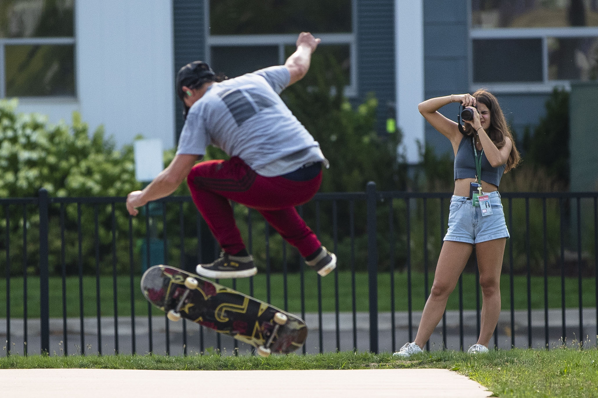 A skateboarder does a trick in the air while a student photographer takes their photo.